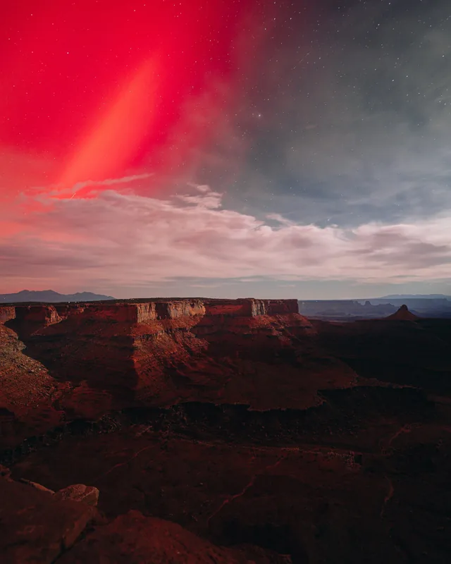 Red aurora over canyon mesas at night