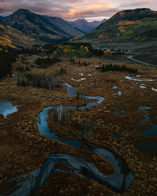 A river winding through autumn wetlands in a mountain valley at dusk