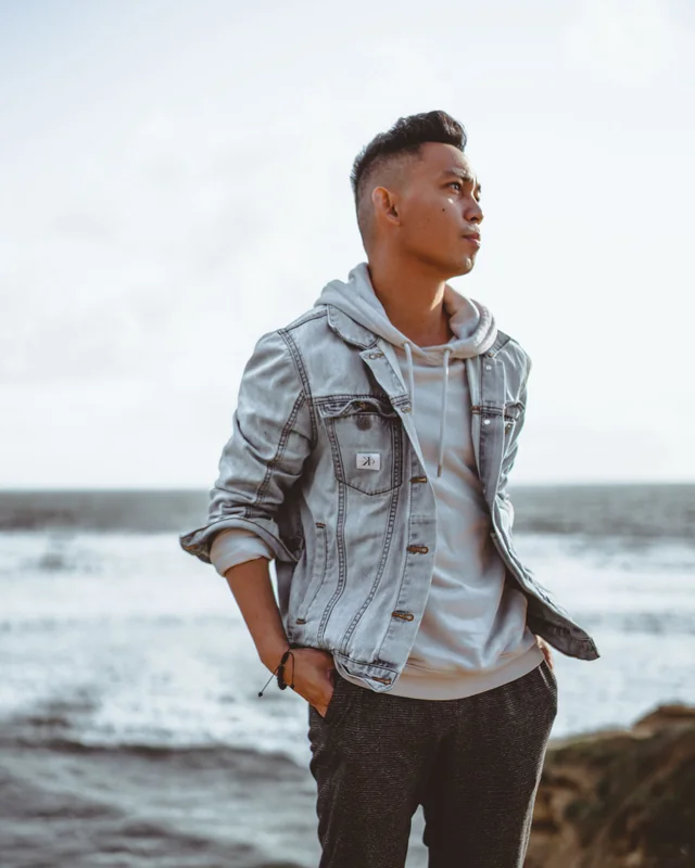 Karyll on a bluff above the sea, hands in his pockets, looking out of frame