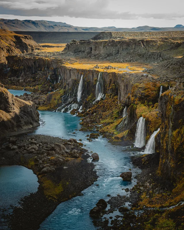 Waterfalls pouring into a blue river canyon in Iceland